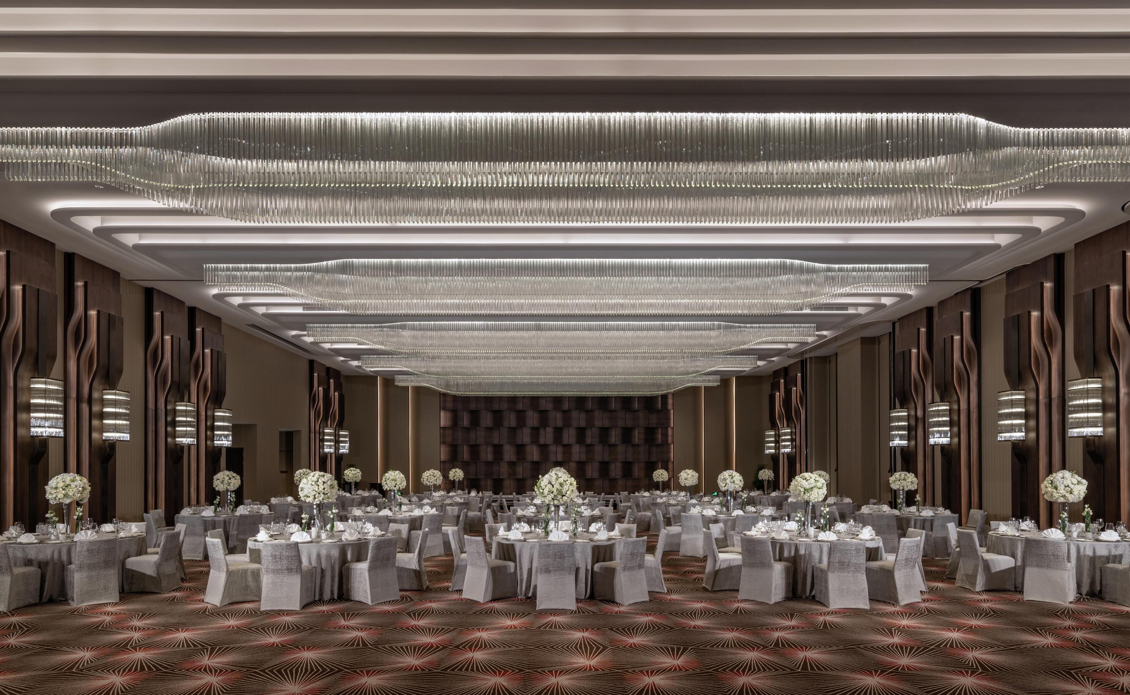 A spacious banquet hall with round tables, chairs, and floral centerpieces.