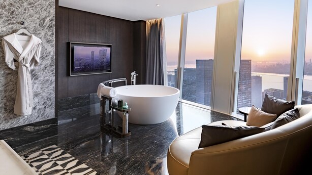 A modern bathroom with a large bathtub, a vanity, and a large window with a city view. - Conrad Hangzhou (Hangzhou)