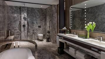 A modern bathroom with a marble shower, a bathtub, and a vanity with a large mirror.