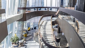 A modern interior with a curved staircase, seating areas, and large windows offering city views. - Conrad Hangzhou (Hangzhou)