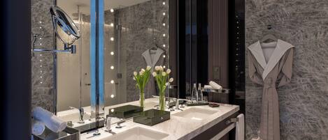 A modern bathroom with two sinks, a large mirror, and a robe hanging on the wall.