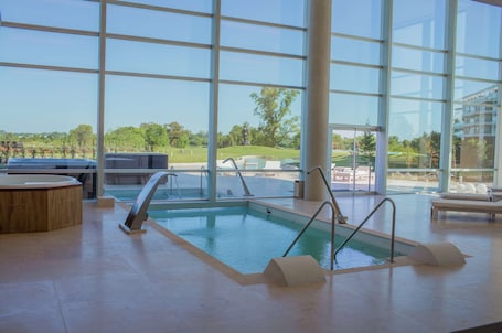 Una piscina techada, una piscina al aire libre de temporada, sombrillas