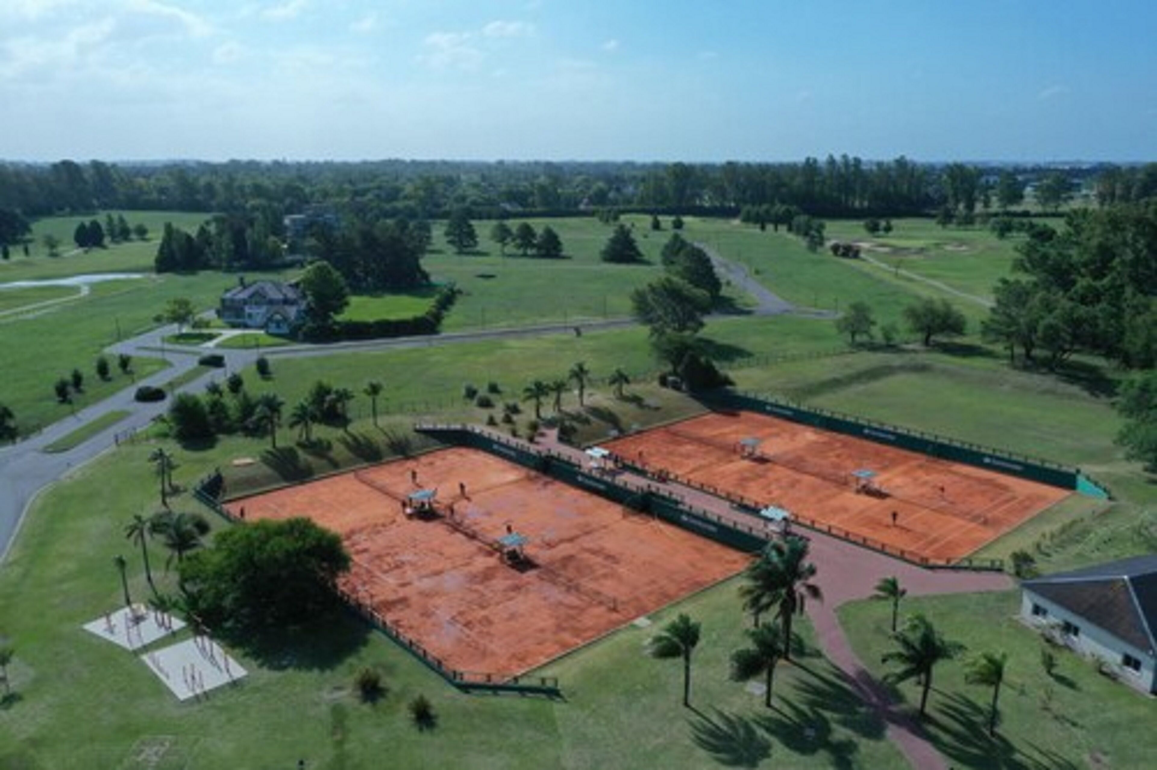 Vista aerea di una proprietà con un'ampia area aperta, circondata dal verde e da alcuni edifici.