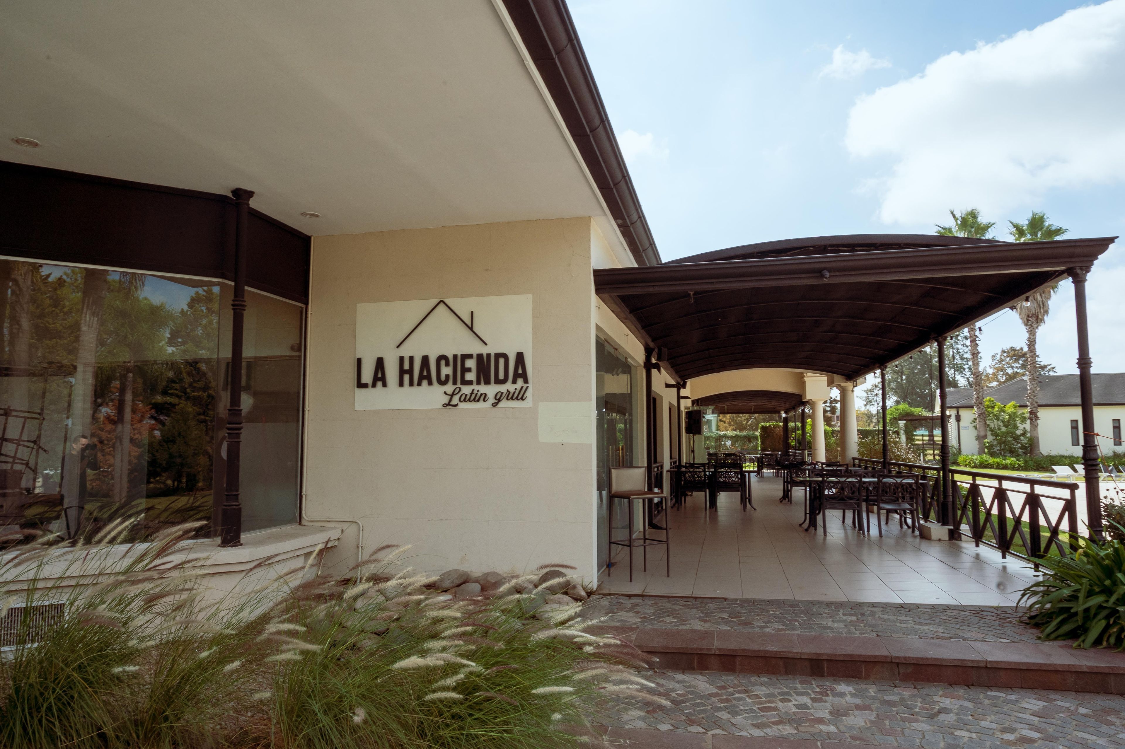 A patio area with outdoor seating and a sign for 'LA HACIENDA Latin grill'.