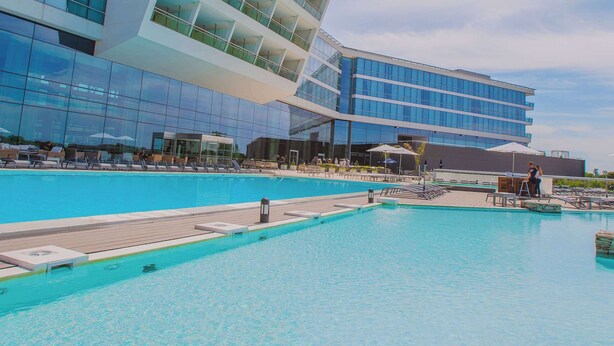 Ein modernes Hotel mit großzügiger Poolanlage, einer Glasfassade und einem einzigartigen architektonischen Design.