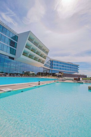 Un hotel moderno con un amplio espacio de piscina, fachada de vidrio y diseño arquitectónico único.