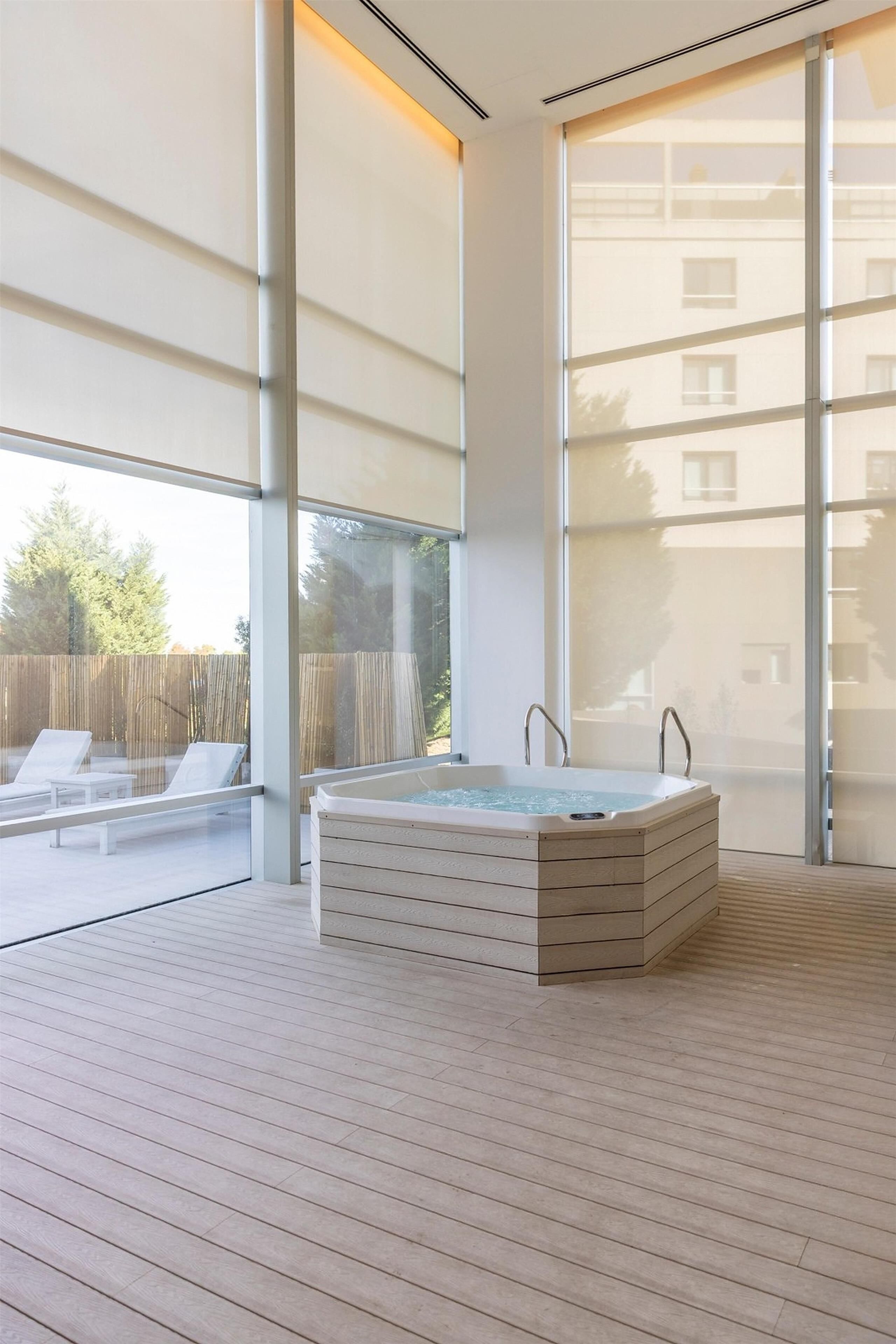 A modern spa area with a hot tub, large windows, and a wooden deck.