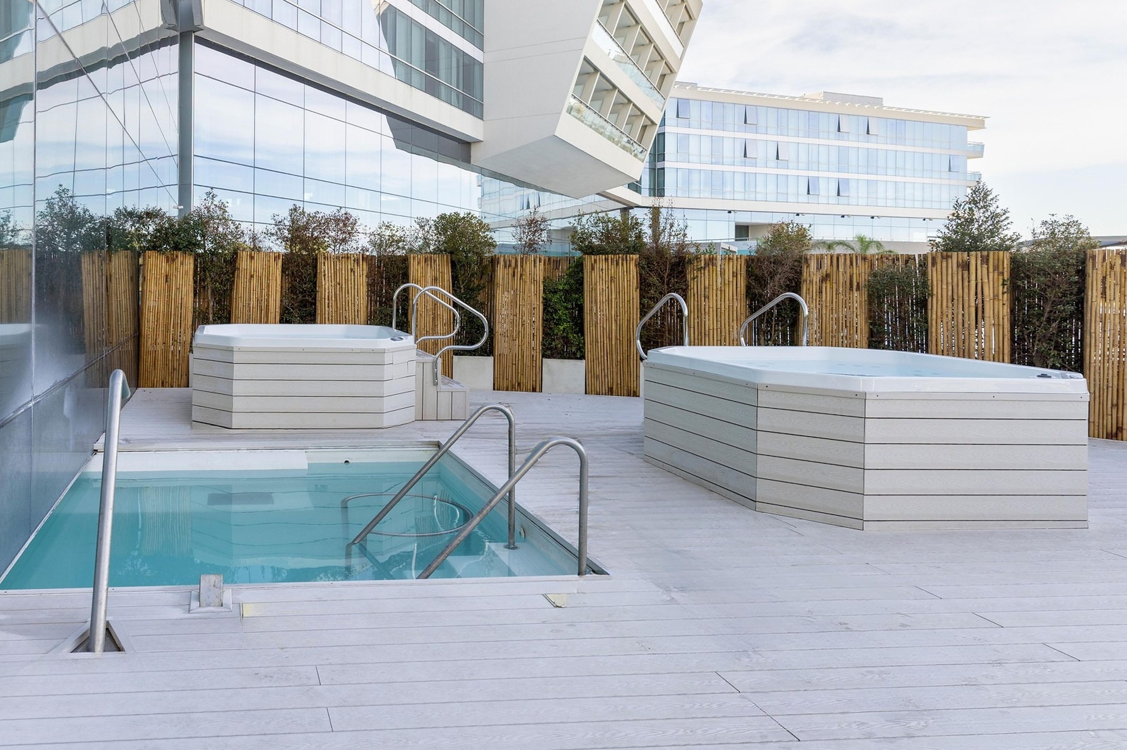 A rooftop pool area with a clear view of the city skyline, surrounded by a wooden fence.