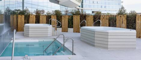 A rooftop pool area with a clear view of the city skyline, surrounded by a wooden fence.