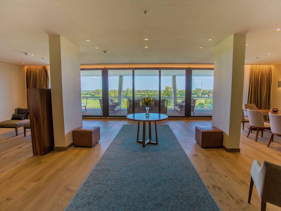 A spacious room with a large window, a round table, and a seating area.