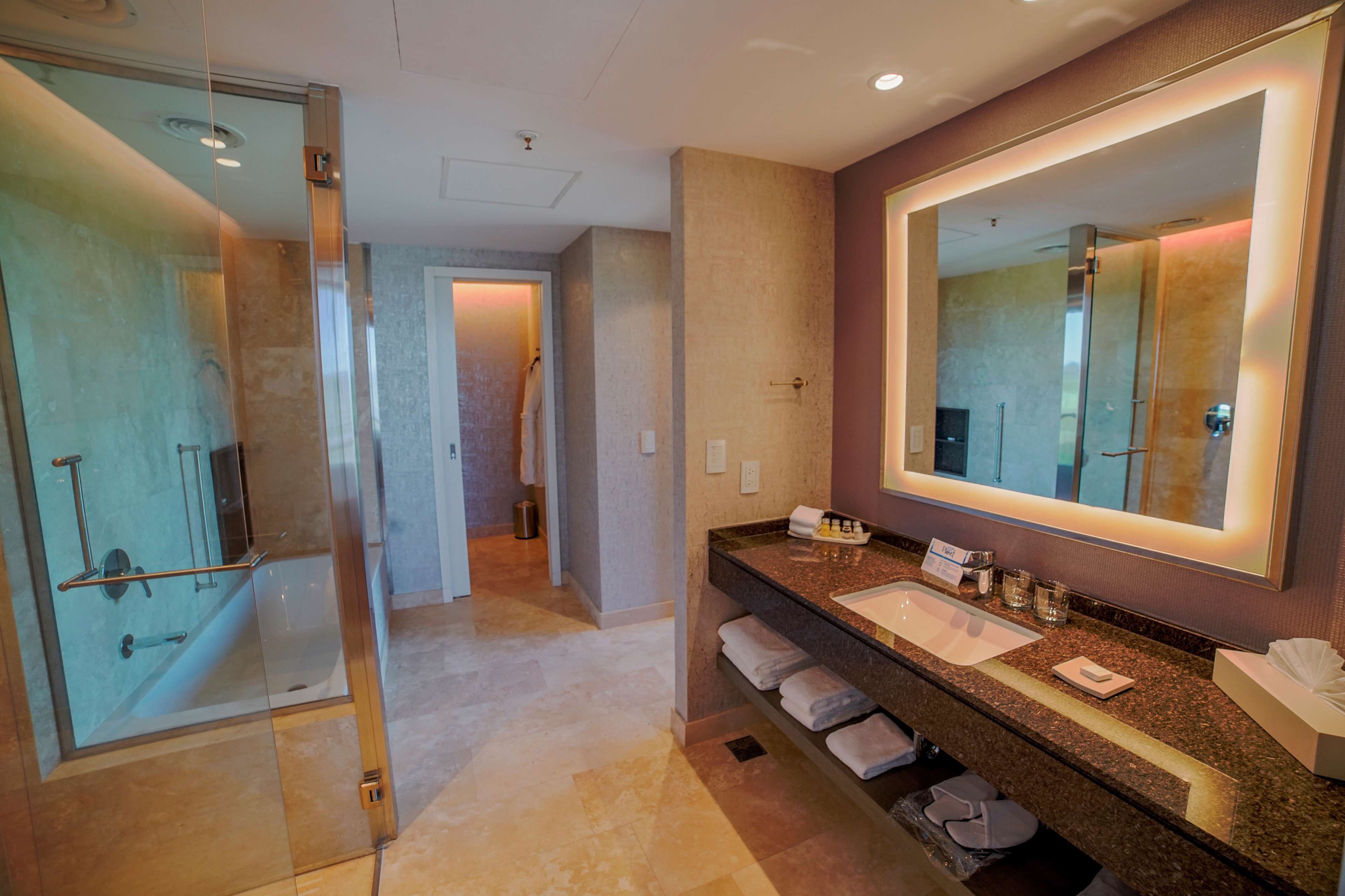 A modern bathroom with a glass-enclosed shower, a large mirror, and a granite countertop with a sink.