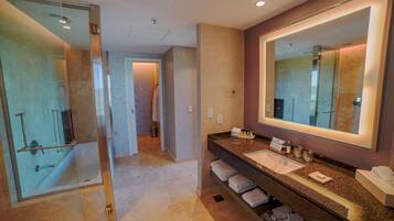 A modern bathroom with a glass-enclosed shower, a large mirror, and a granite countertop with a sink.