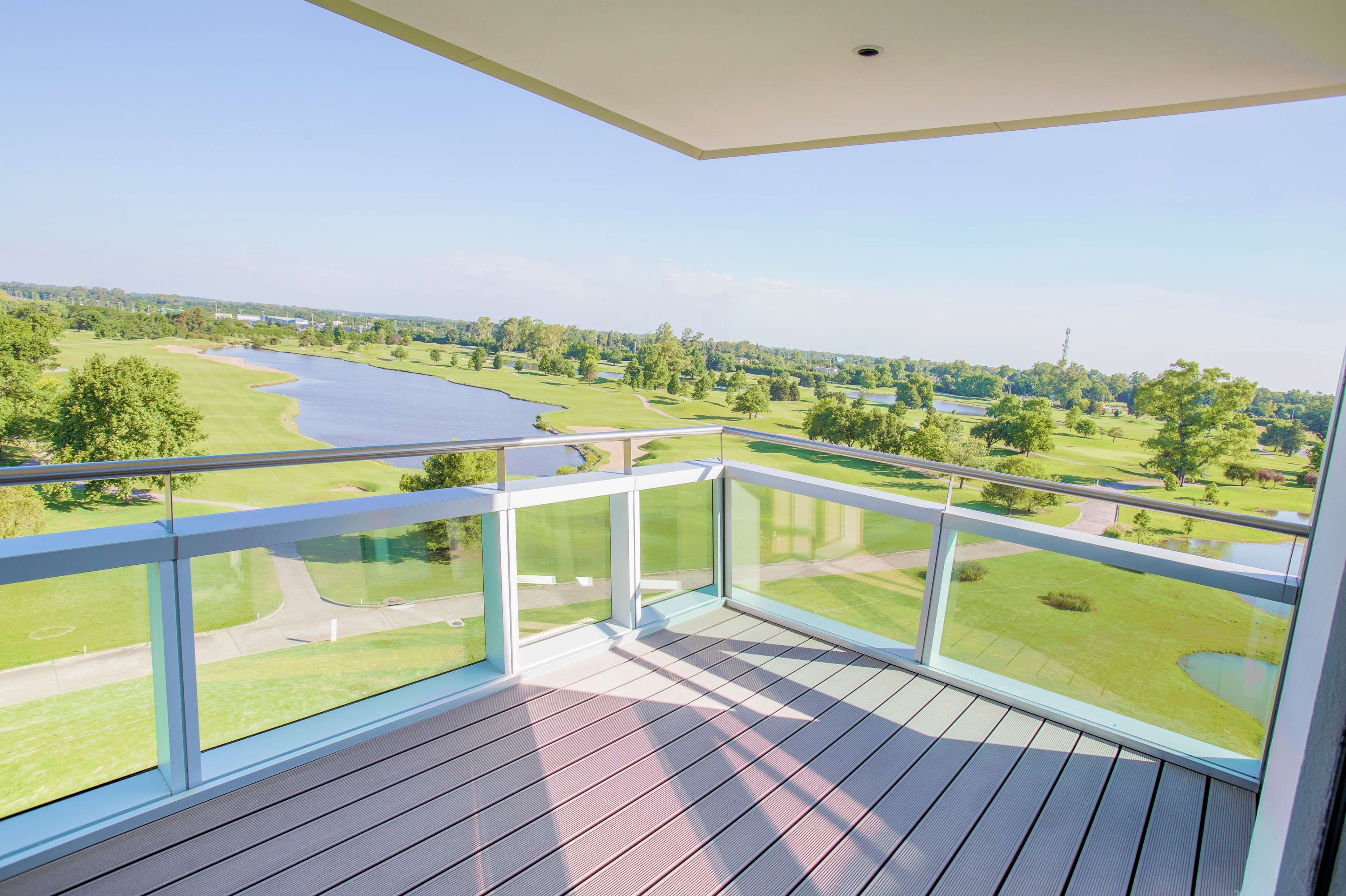 A balcony with a view of a golf course and a body of water.