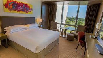 Habitación de hotel con una cama grande, un escritorio, una silla y vista a un campo de golf.