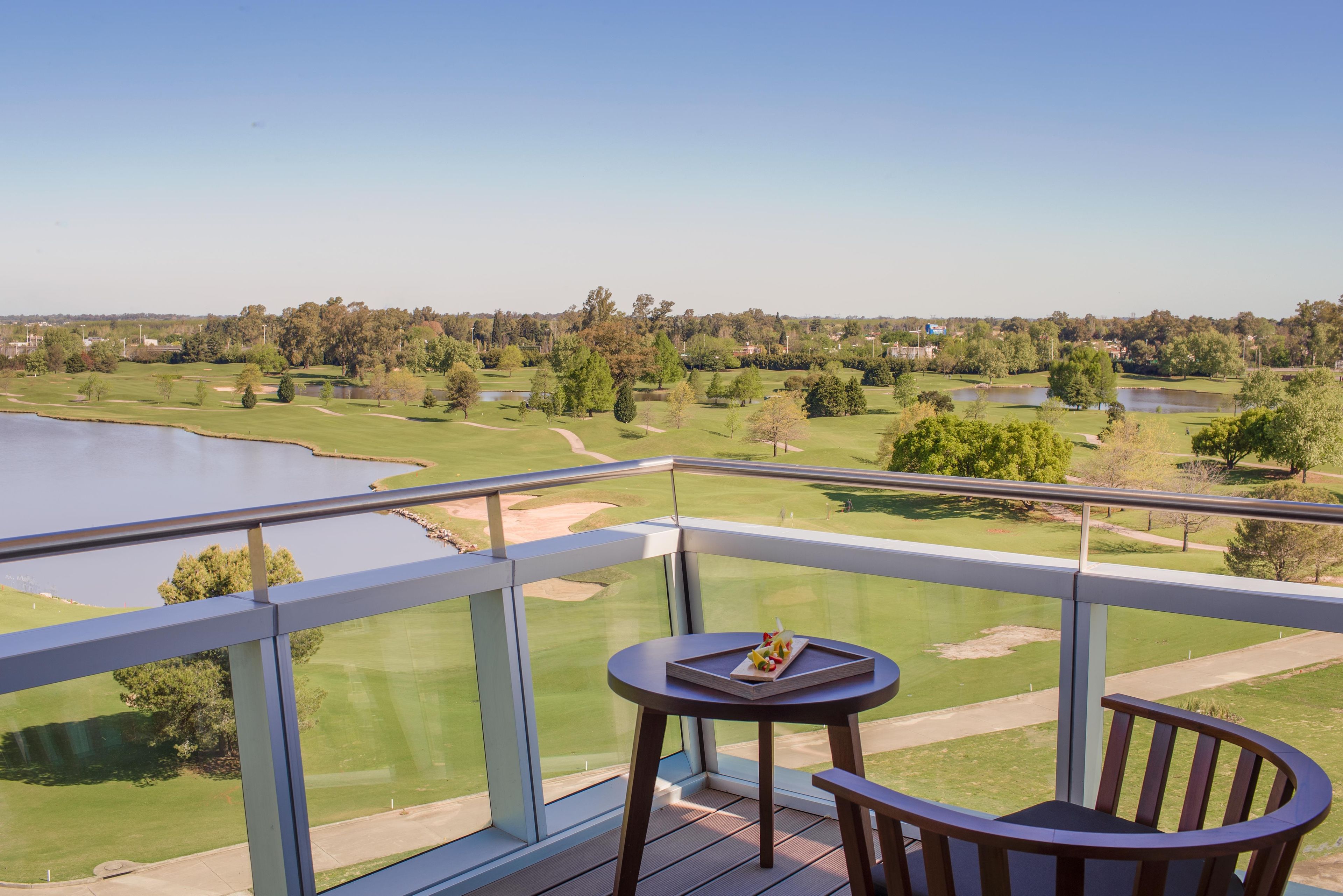 A balcony with a view of a golf course and a body of water.