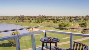 A balcony with a view of a golf course and a body of water.