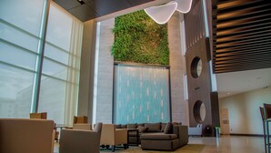 Eine geräumige Lobby mit modernen Möbeln, einer vertikalen Grünwand und einem großen Fenster.