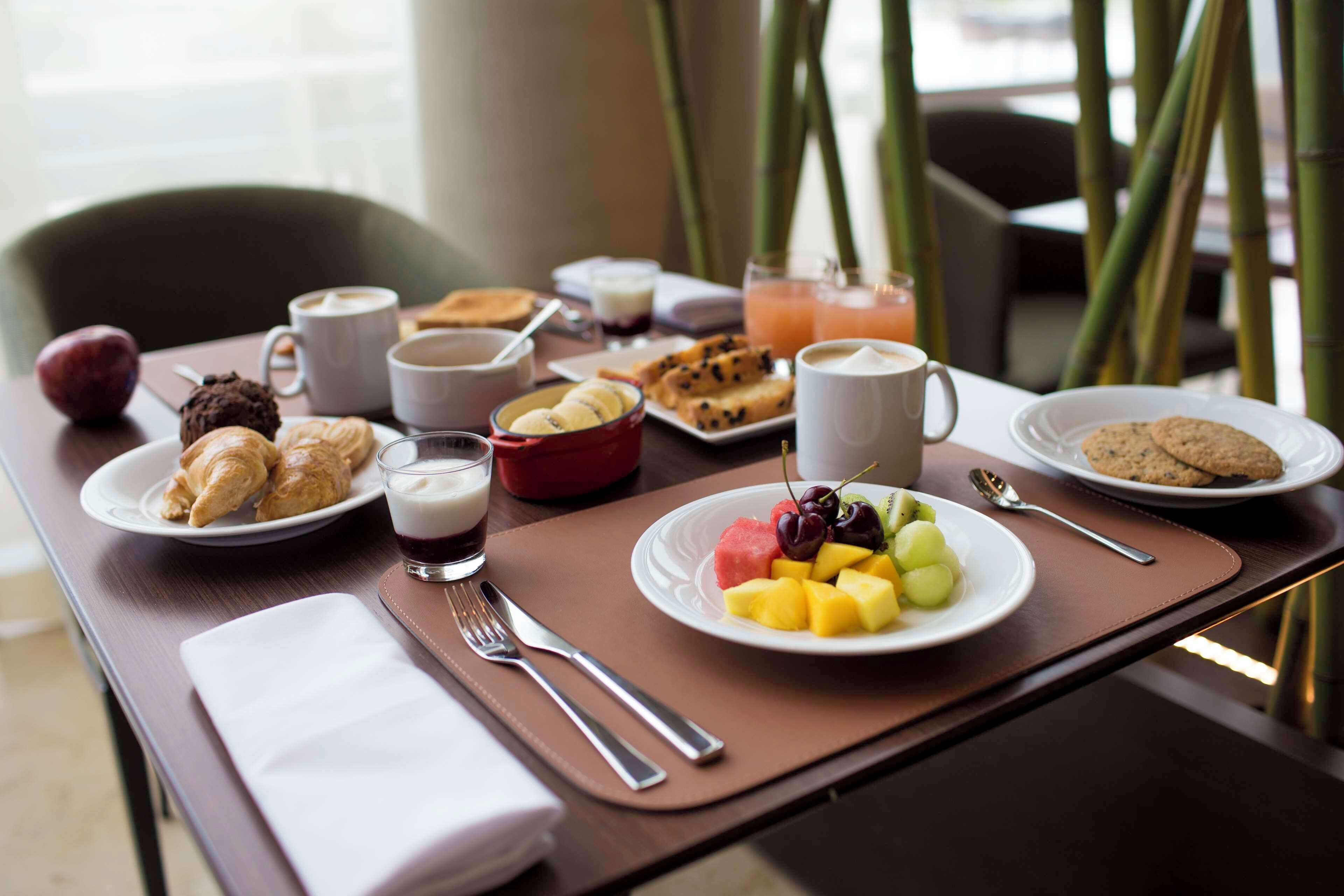 Una mesa de desayuno con cruasanes, fruta, galletas y bebidas.