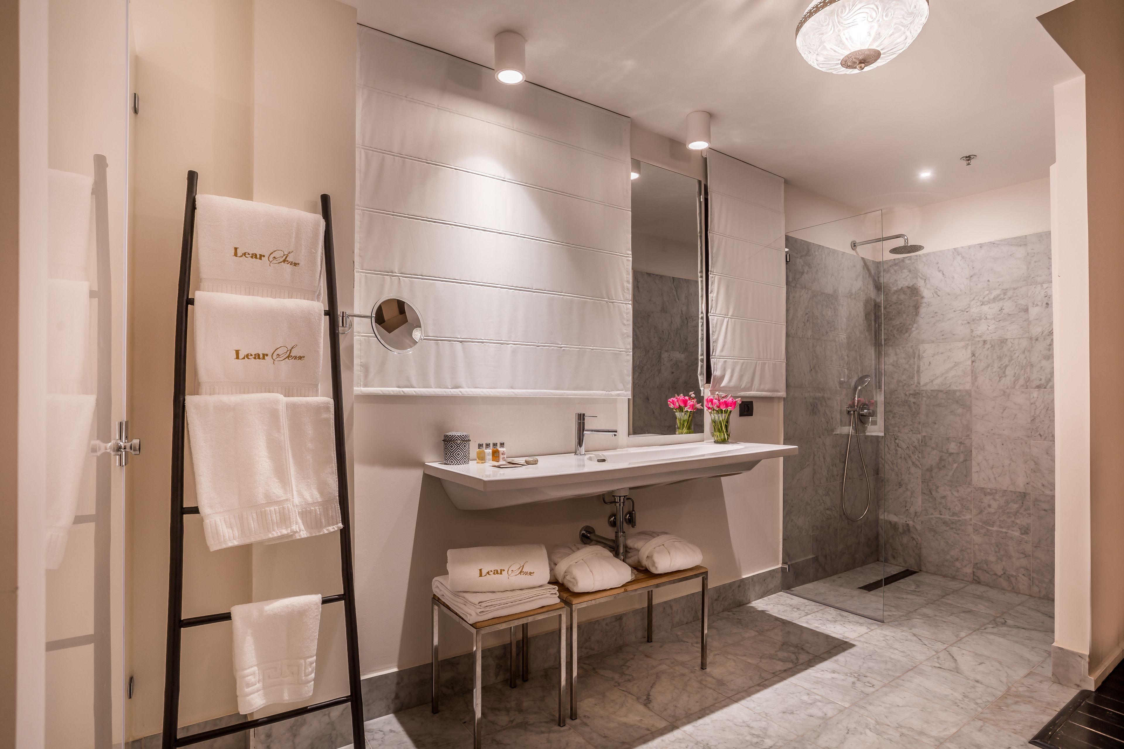Ein modernes Badezimmer mit Glasdusche, Waschtisch mit Spiegel und Handtuchhalter mit Handtüchern.