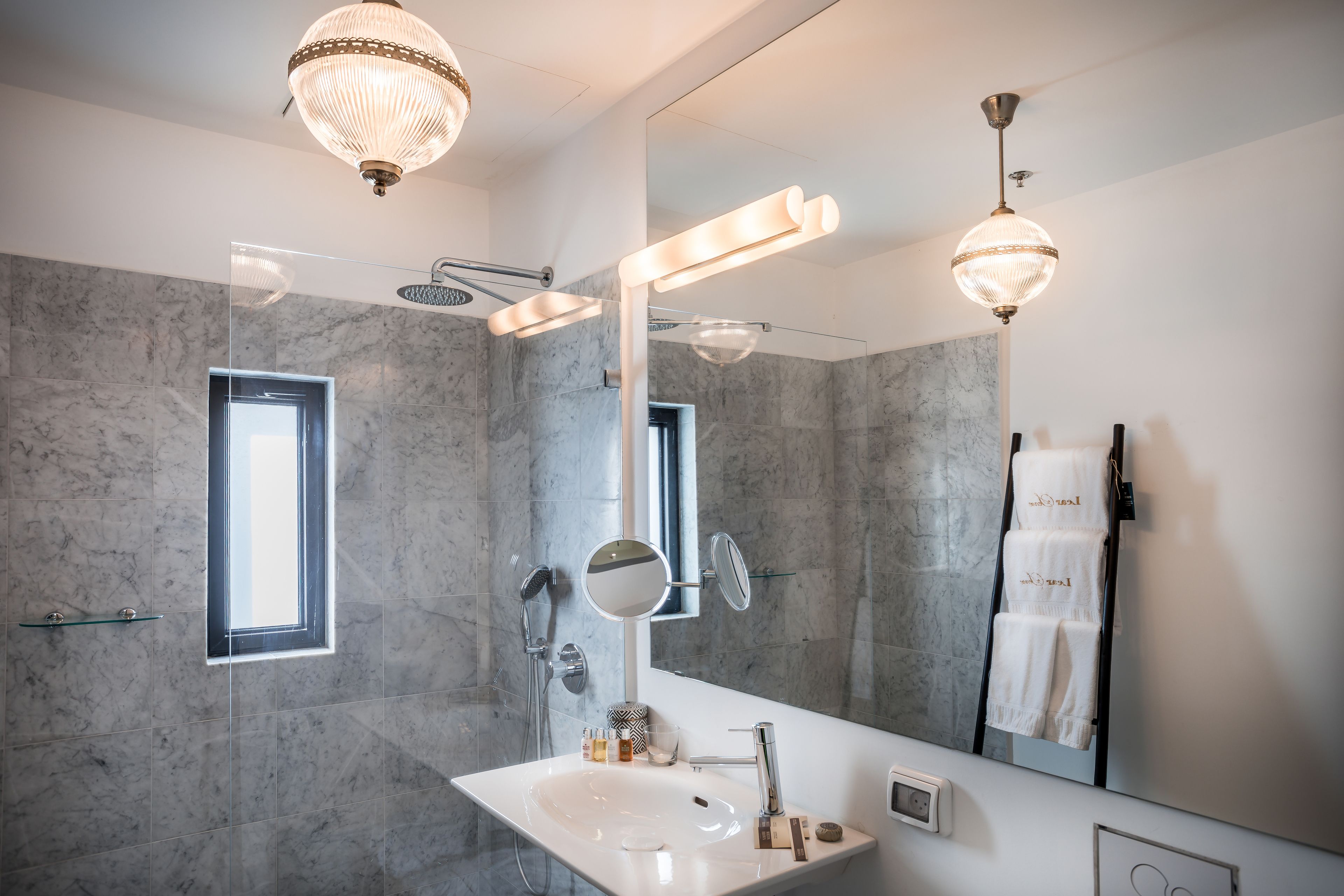 Une salle de bain moderne avec un grand miroir, un lavabo et un espace douche.
