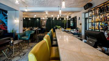 Zona de bar con mostrador de mármol, asientos de cuero y una variedad de botellas.