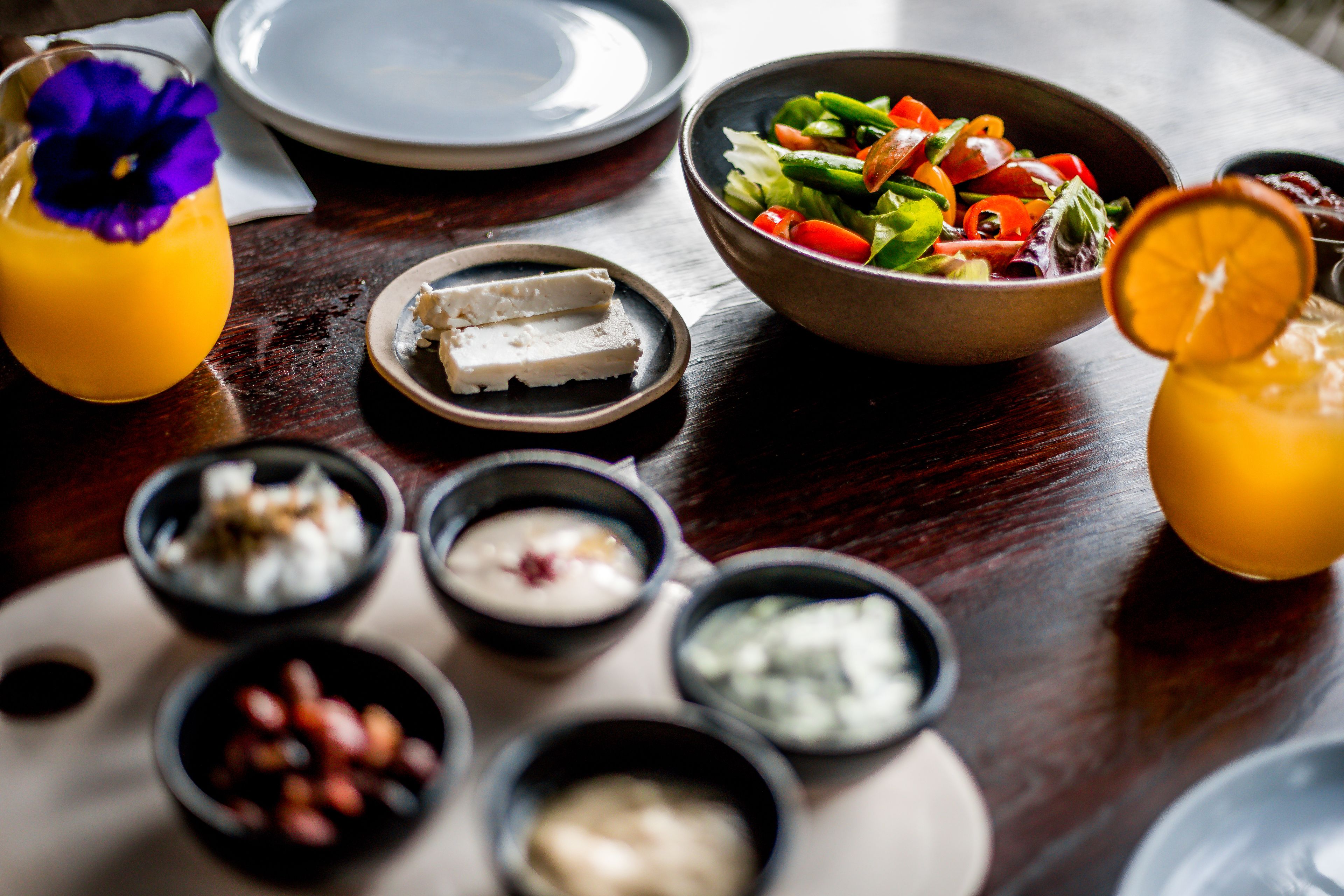 A dining table with a variety of food items including a salad, cheese, and drinks.