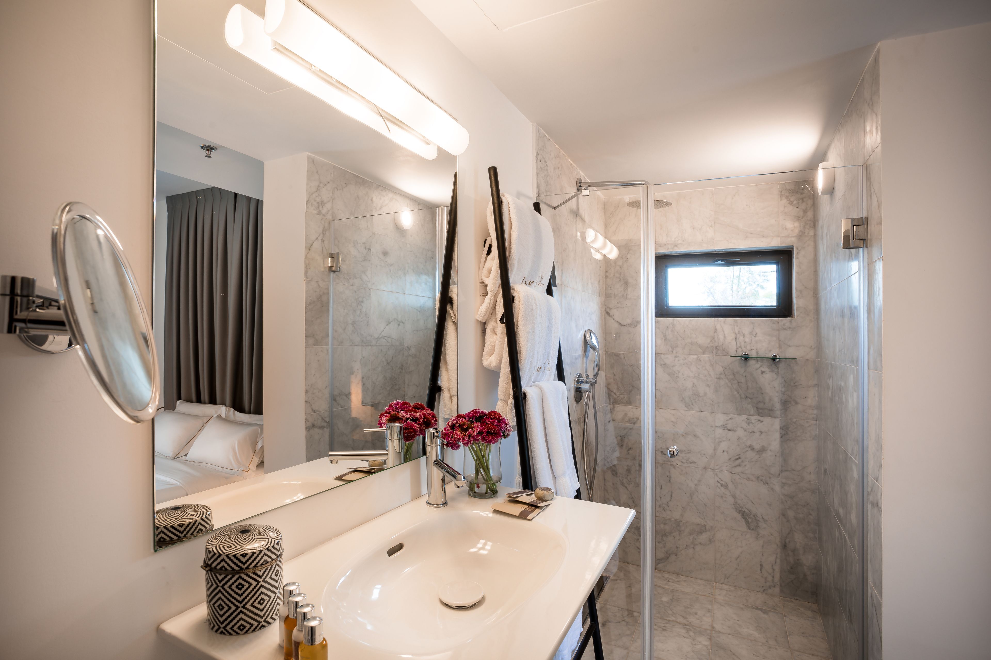 Un baño moderno con un espejo grande, un lavabo blanco y una zona de ducha.