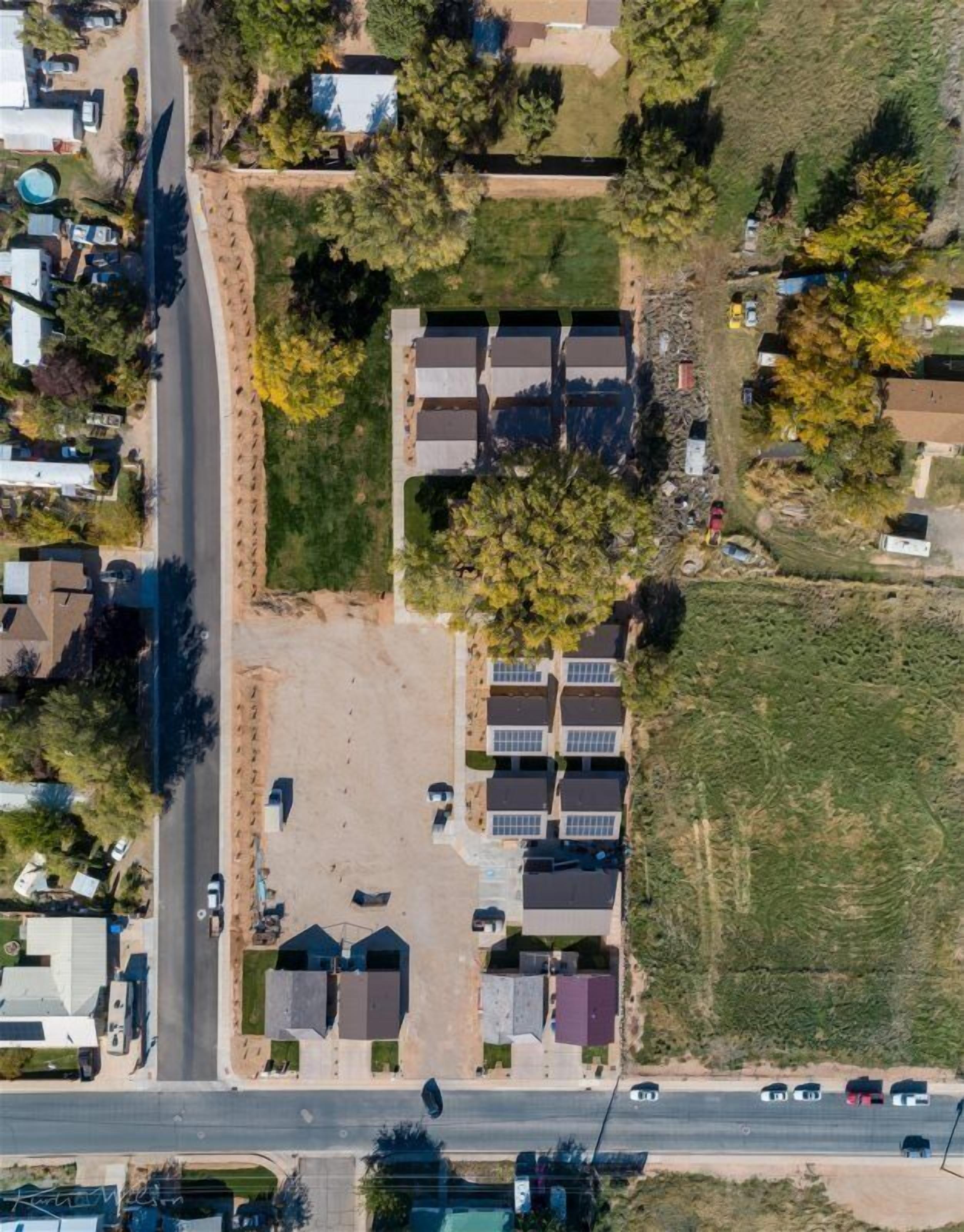 Vista aérea de una zona residencial con casas, una carretera y un estacionamiento pequeño.