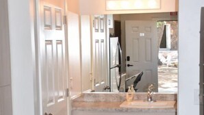 A bathroom with a large mirror, a sink, and a shower. - Zion's Camp and Cottages (La Verkin)