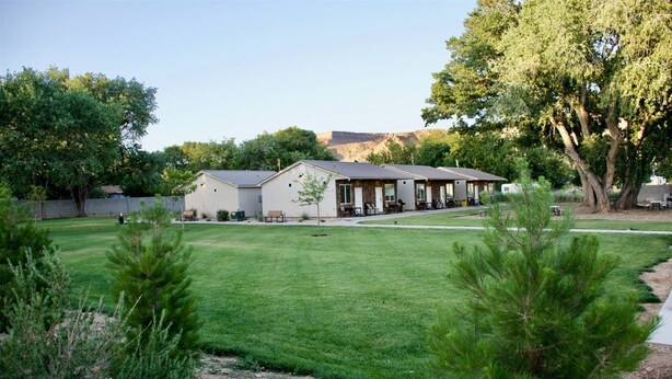 A row of single-story buildings with a flat roof, likely a motel or inn, surrounded by a well-maintained lawn and trees. - Zion's Camp and Cottages (La Verkin)
