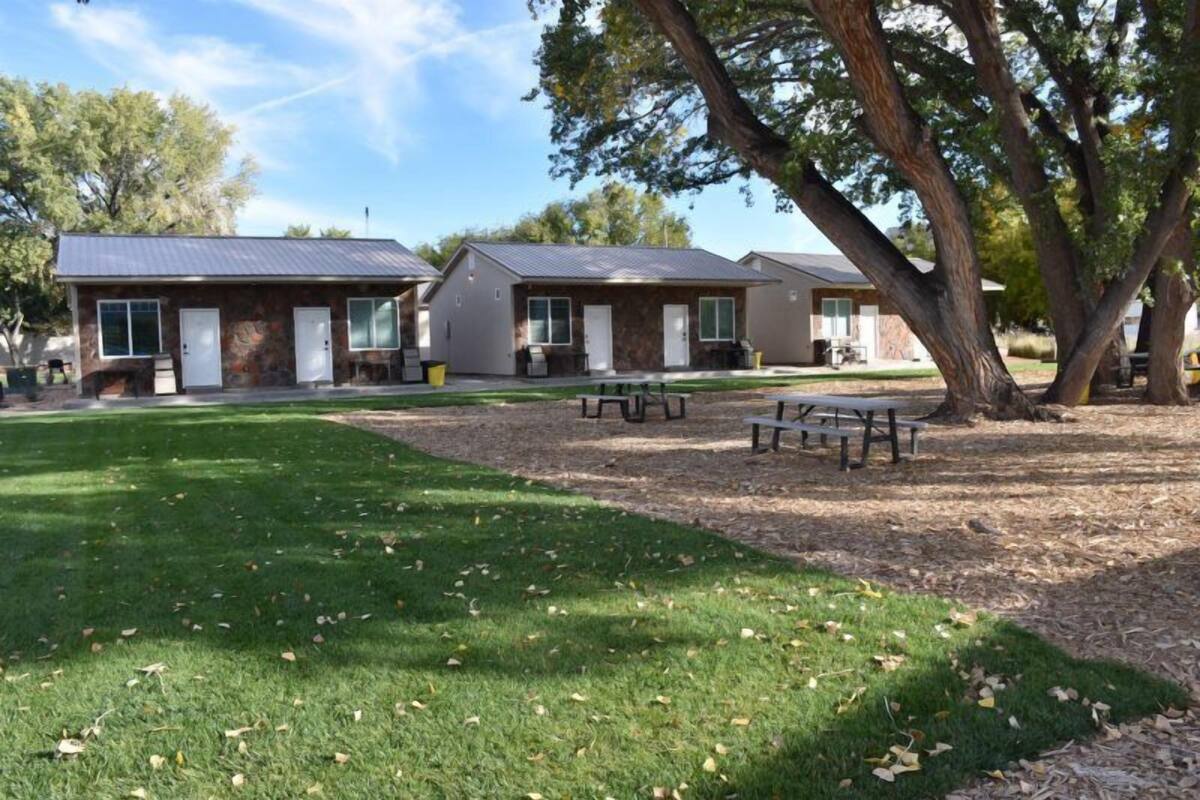 A row of motel-style buildings with a grassy lawn and picnic tables.