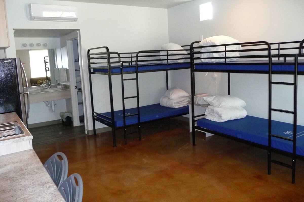 A bunk room with two bunk beds, a sink, and a mirror.
