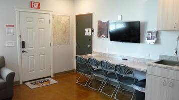 A compact kitchen with a dining area, a flat-screen TV, and a map on the wall.