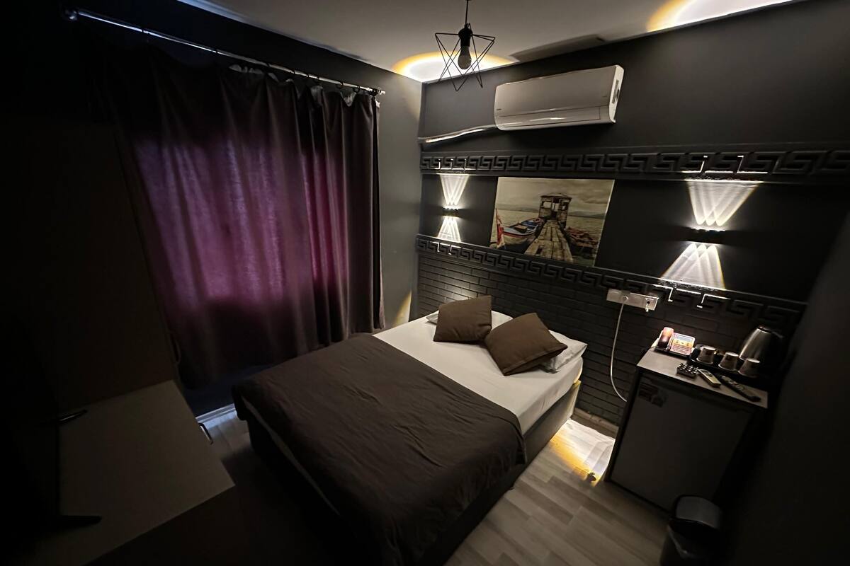 A modern bedroom with a bed, bedside table, and a small desk with a lamp.