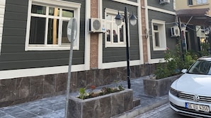 A multi-story building with air conditioning units, decorative window frames, and a street lamp. - Asus Palmiye Otel (Adana)