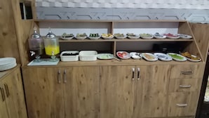A wooden buffet setup with various food items and a juice dispenser. - Asus Palmiye Otel (Adana)