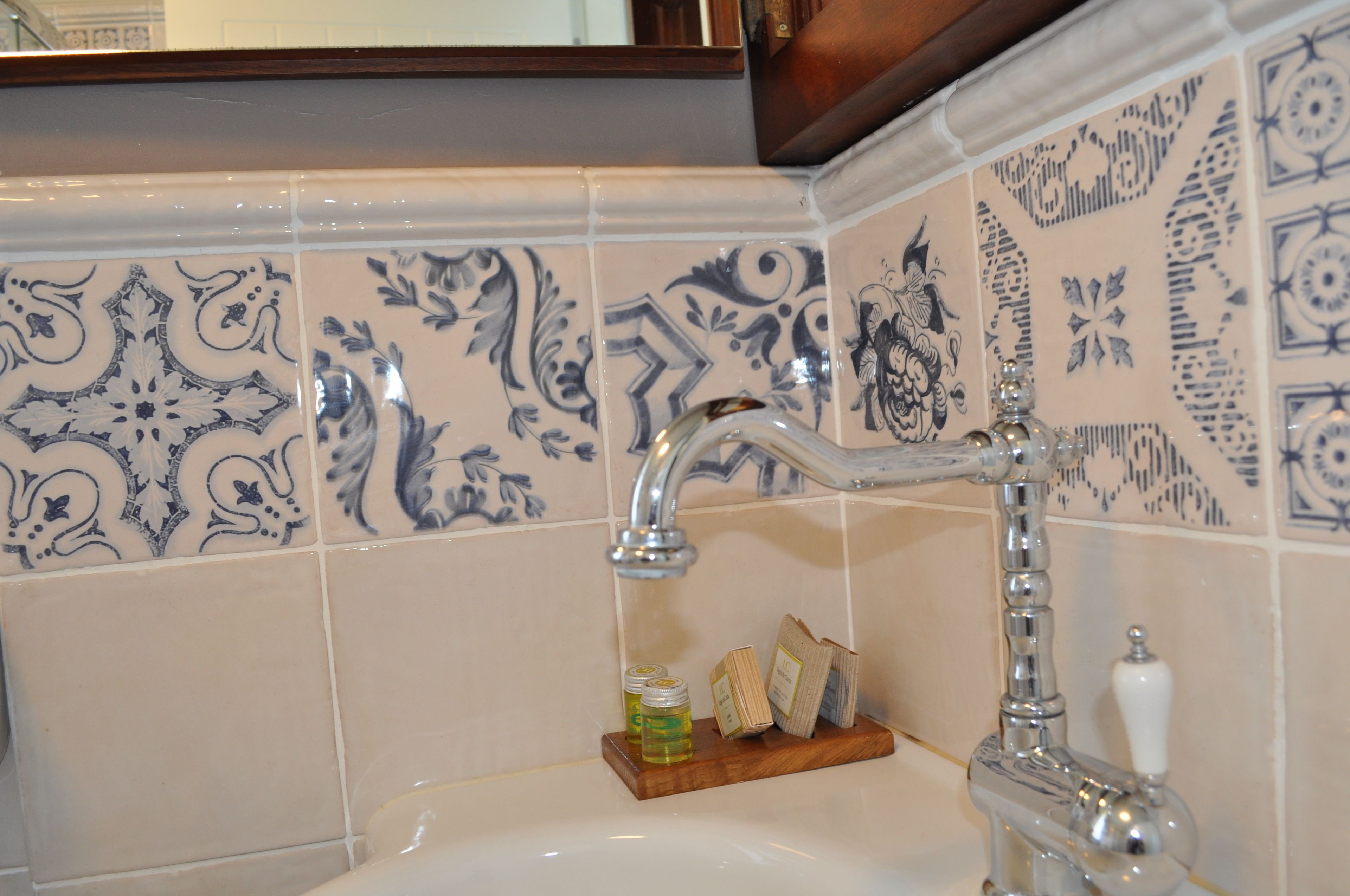 A bathroom with a sink, a mirror, and decorative blue and white tiles.