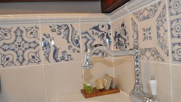 A bathroom with a sink, a mirror, and decorative blue and white tiles.