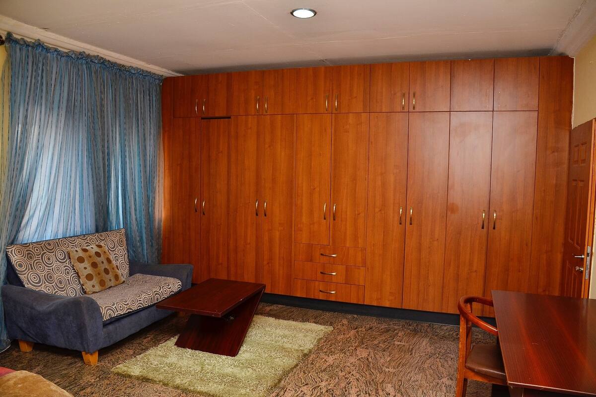 Una habitación con sofá, armario de madera, mesa de comedor y una mesita de centro.