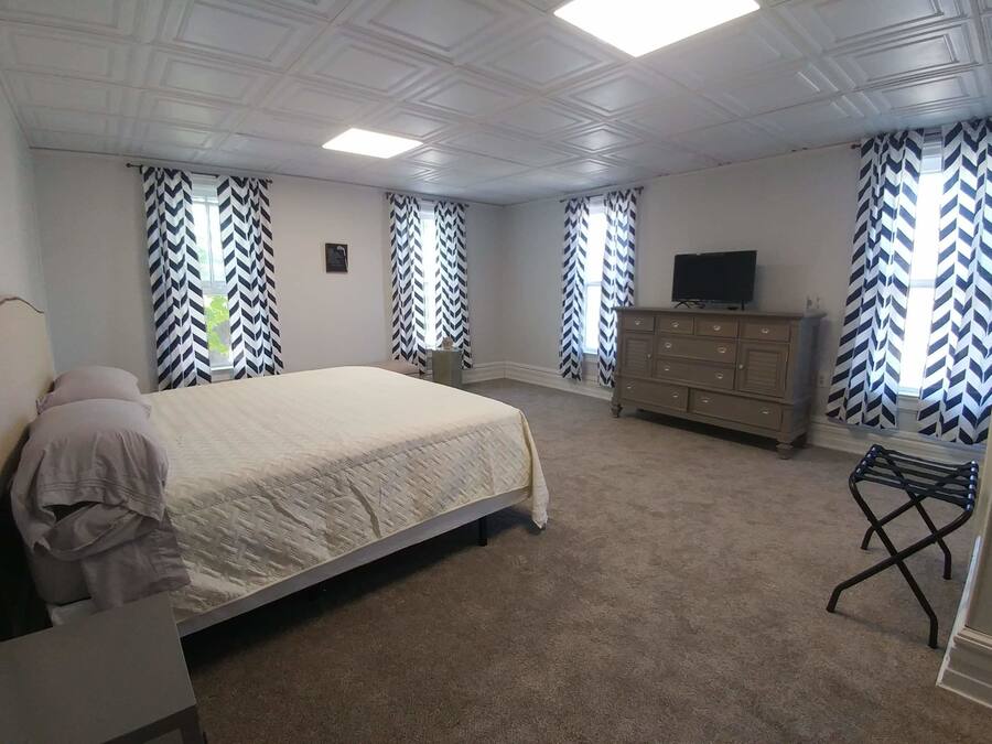 Un dormitorio con cama, cómoda, televisión y una silla.