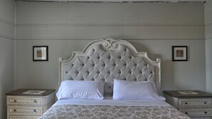 Una cama bien hecha con un cabecero capitonado, dos mesitas de noche y ropa de cama con estampado floral.