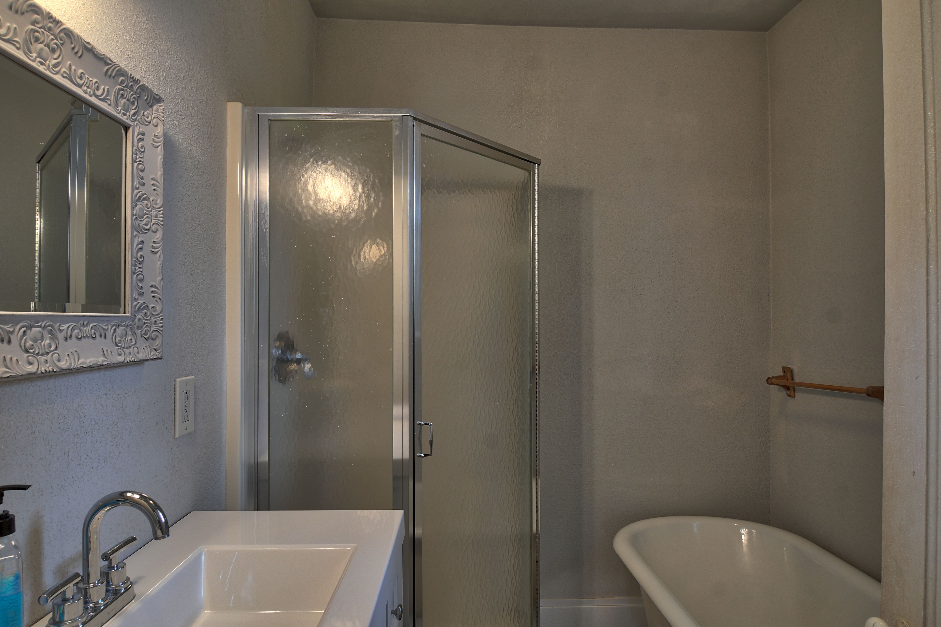 Un bagno con doccia vetrata, una vasca da bagno bianca e un lavandino con specchio.