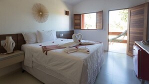 Habitación de hotel con una cama grande, una mesita de noche con lámpara, vistas al exterior a través de una ventana y una hamaca en una esquina.