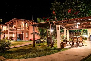 A multi-story building with a covered outdoor area featuring a pool table and seating. - Pousada Porto Manguaba (Japaratinga)