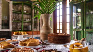 Una mesa con diversos postres y un jarrón con plantas verdes.