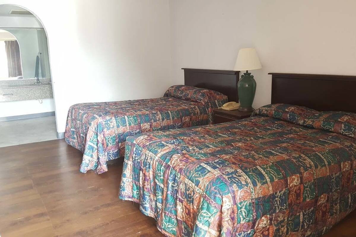 A room with two beds, a nightstand with a lamp, and a telephone.