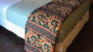 A hotel room with two beds, a nightstand with a lamp, and a painting on the wall. - Cactus Inn and Suites (Copperas Cove)