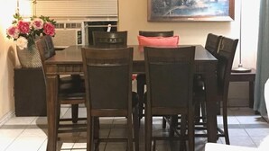 A dining area with a table and chairs, a painting on the wall, and a vase with flowers. - Cactus Inn and Suites (Copperas Cove)