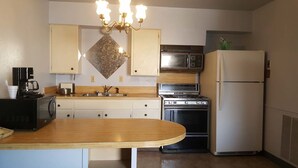 A kitchen with a wooden countertop, a stove, a microwave, and a refrigerator. - Cactus Inn and Suites (Copperas Cove)