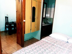 A bedroom with a bed, a wooden wardrobe, a desk with a chair, and a bathroom with a mirror and sink. - El Rinconcito (Puerto Iguazú)